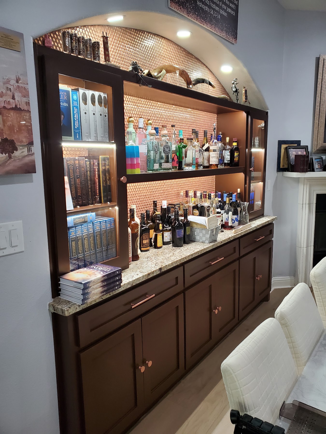Completed custom arched home bar with dark cabinetry and illuminated shelving