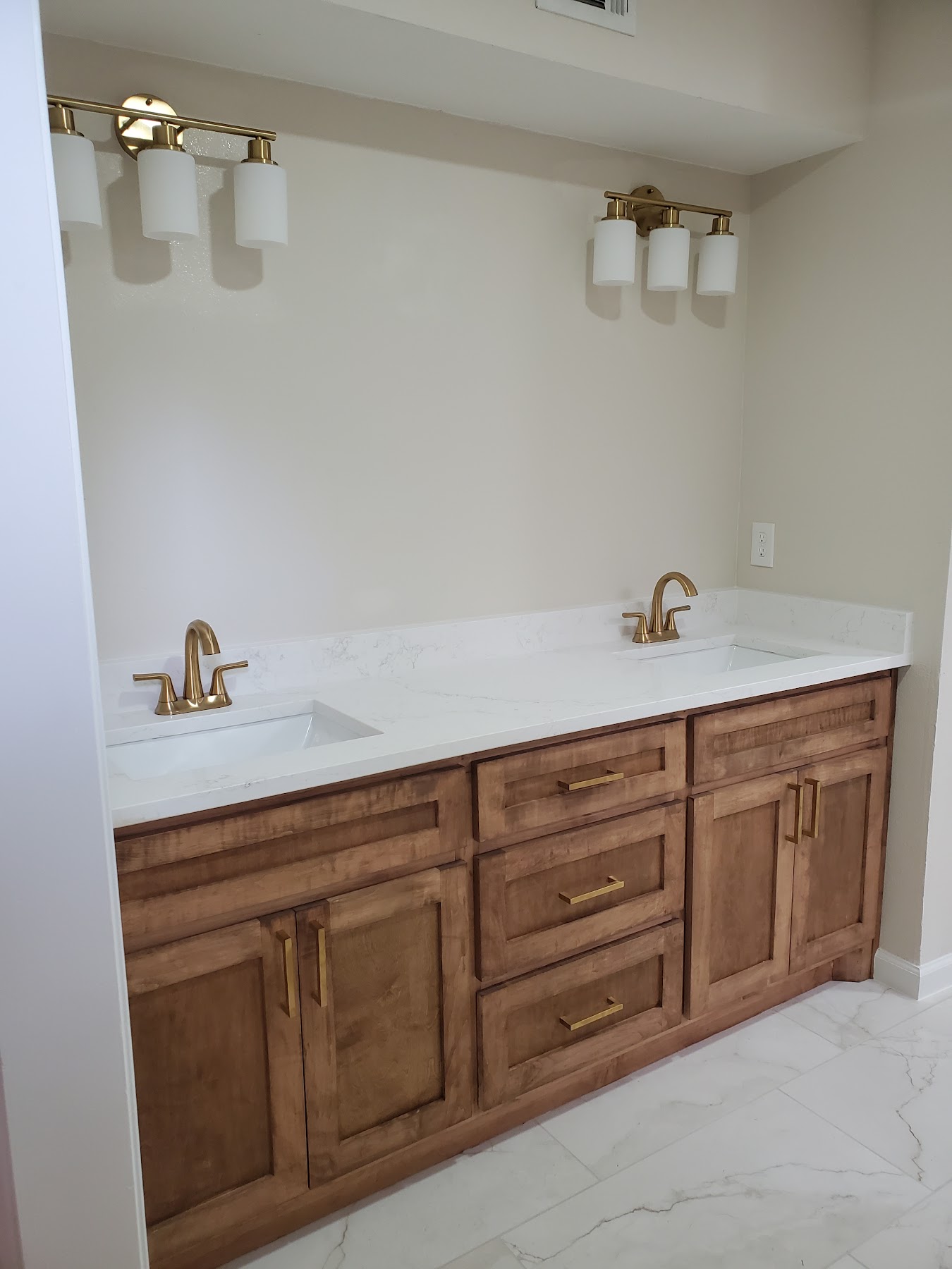 Completed double bathroom vanity with wood cabinetry and brass fixtures