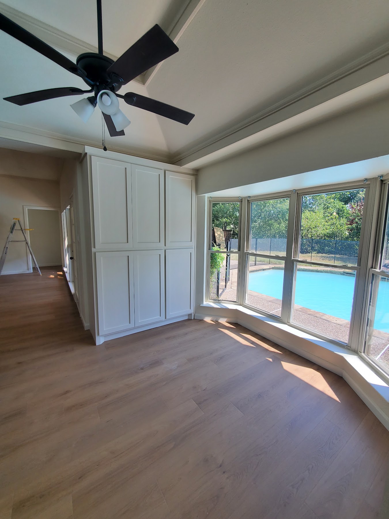 Completed open living space with new flooring, custom built-ins, and pool-facing windows